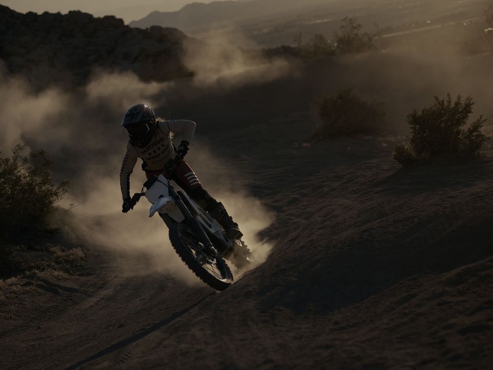 A rider on a white Bonnell electric bike carving through dust at dusk