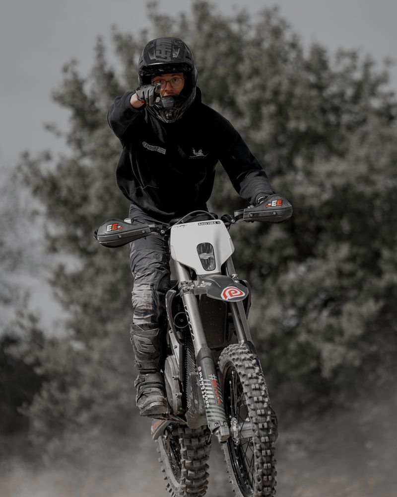 A rider on a Stark Varg pointing at the camera as the bike lands off a jump on our track